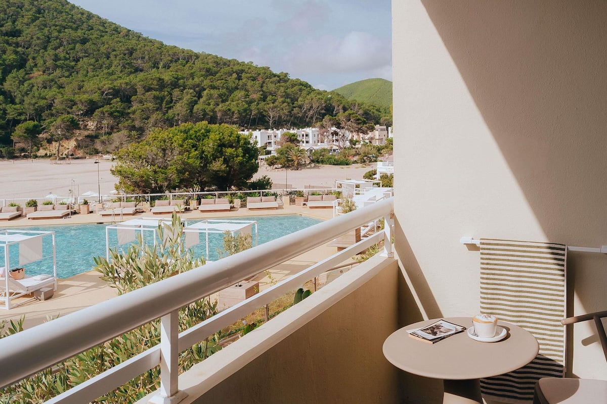 Un balcon avec une piscine, des chaises longues et une table avec une tasse.