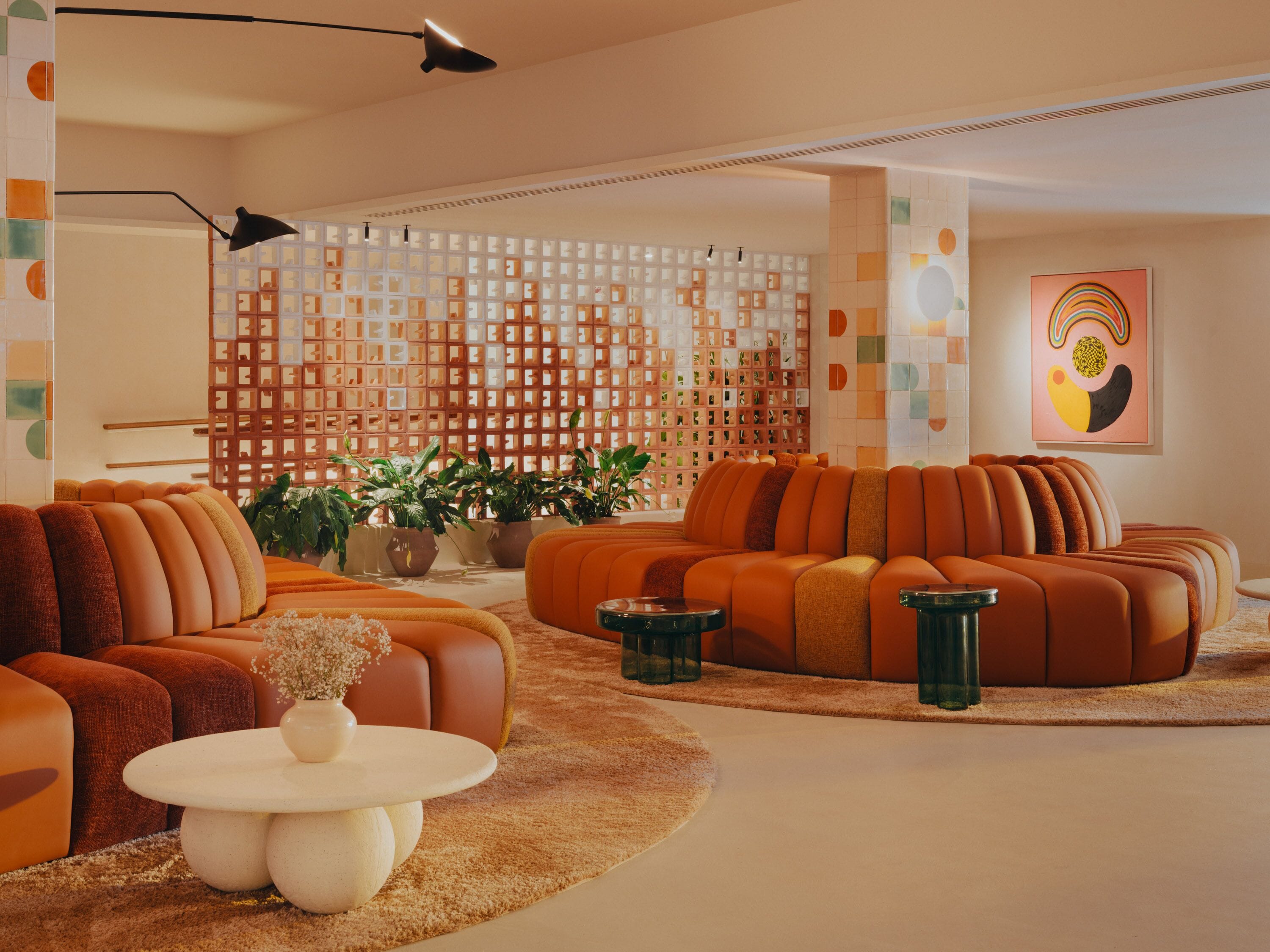 Un salon moderne avec un canapé d’angle, une table basse et un mur décoratif orné de motifs géométriques.