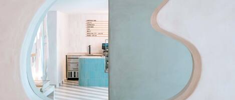 A modern interior with a unique mirror design, a kitchenette, and a staircase.