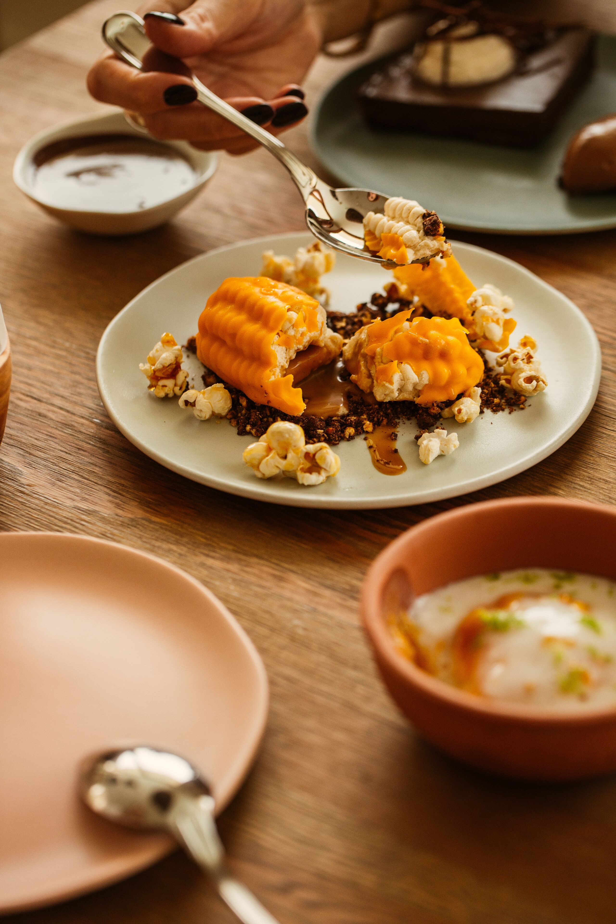 A dessert plate with caramel and popcorn on a wooden table.