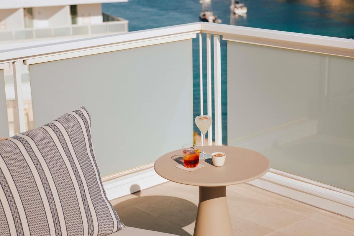 Un balcon avec une table ronde, un coussin et un verre à boire.