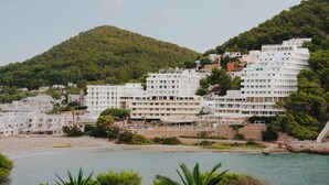 Une ville côtière aux bâtiments blancs, avec une plage et une colline en arrière-plan.