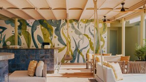 A spacious indoor area with a large mural, a seating area with a sofa and chairs, and a hanging chair. - Hyde Ibiza (Santa Eulalia del Rio)