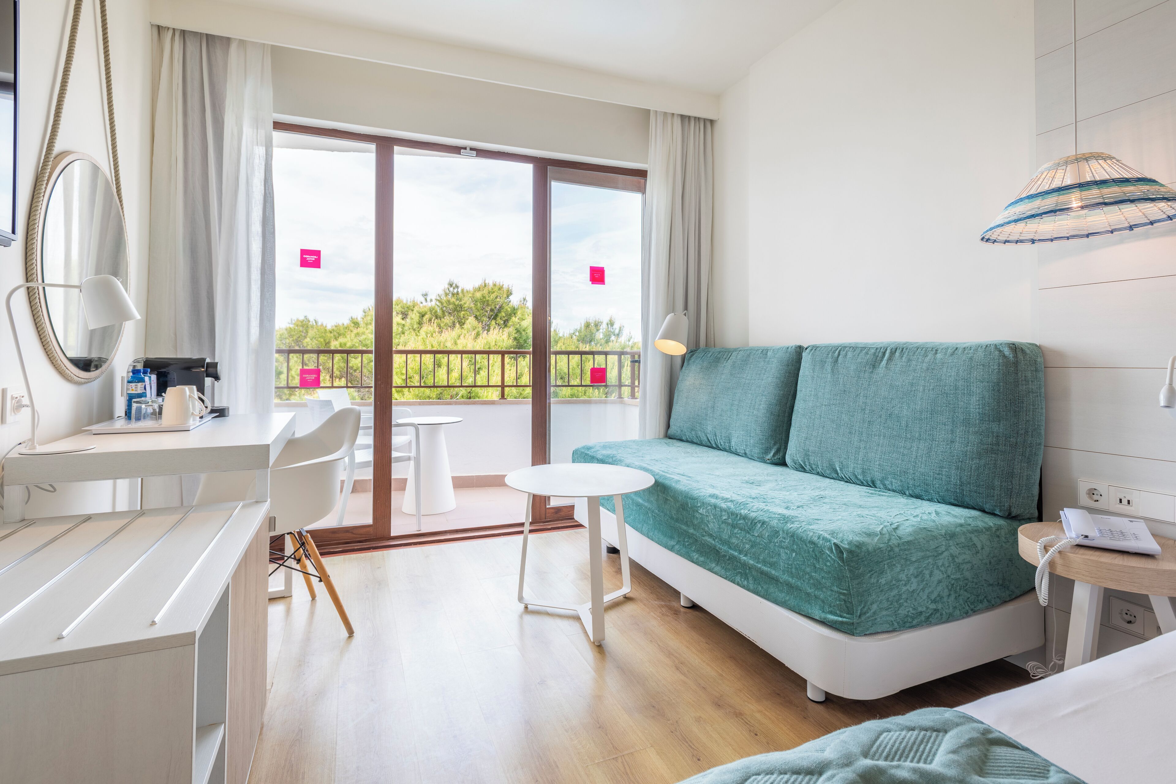 Una habitación de hotel moderna con sofá, escritorio, silla, una mesita y un balcón con vistas.
