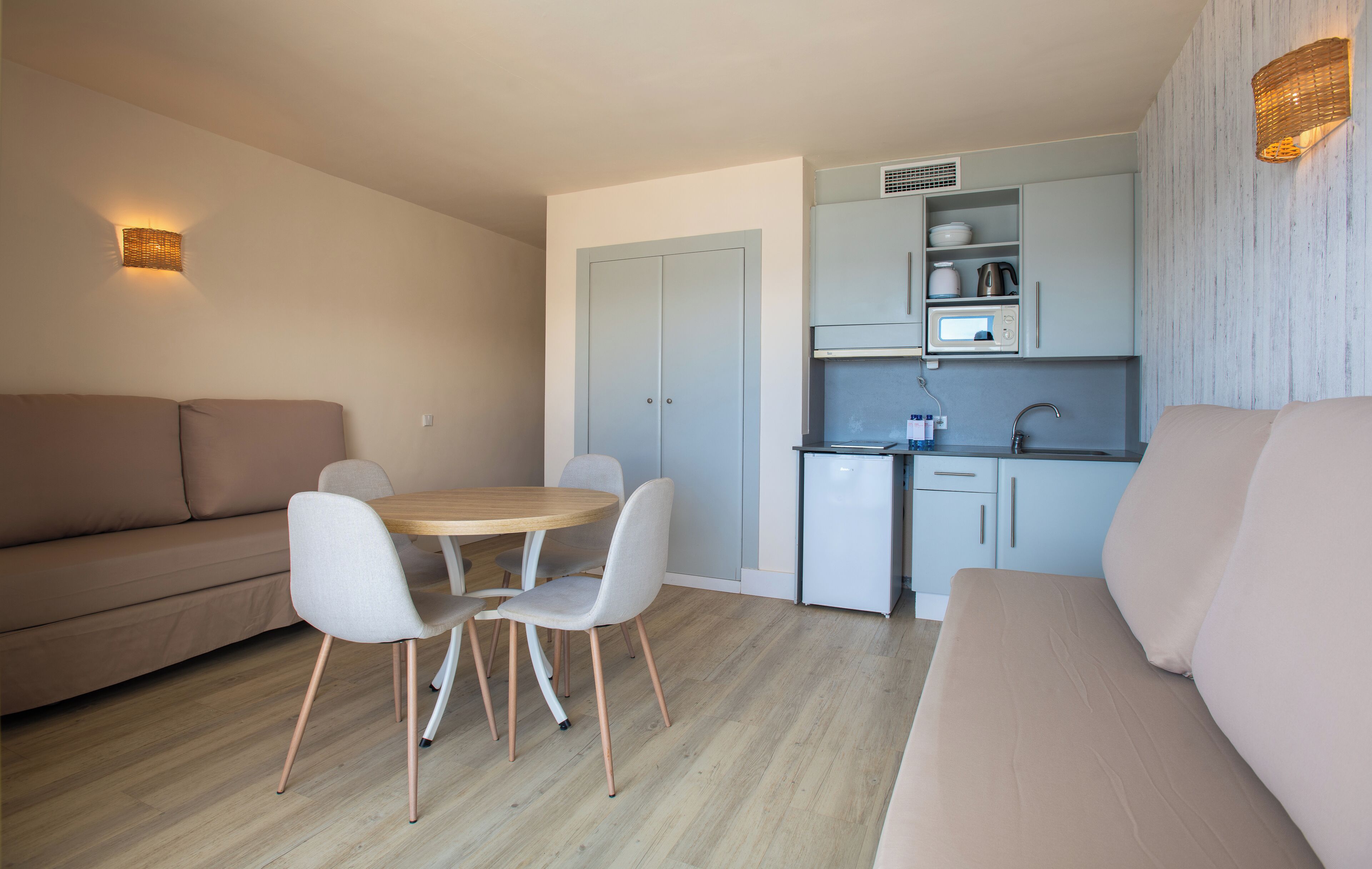 A compact living space with a kitchenette, a dining area, and two sofas.