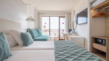 Une chambre d’hôtel comprenant un lit, un bureau, une chaise, une télévision et un balcon avec une table et des chaises.