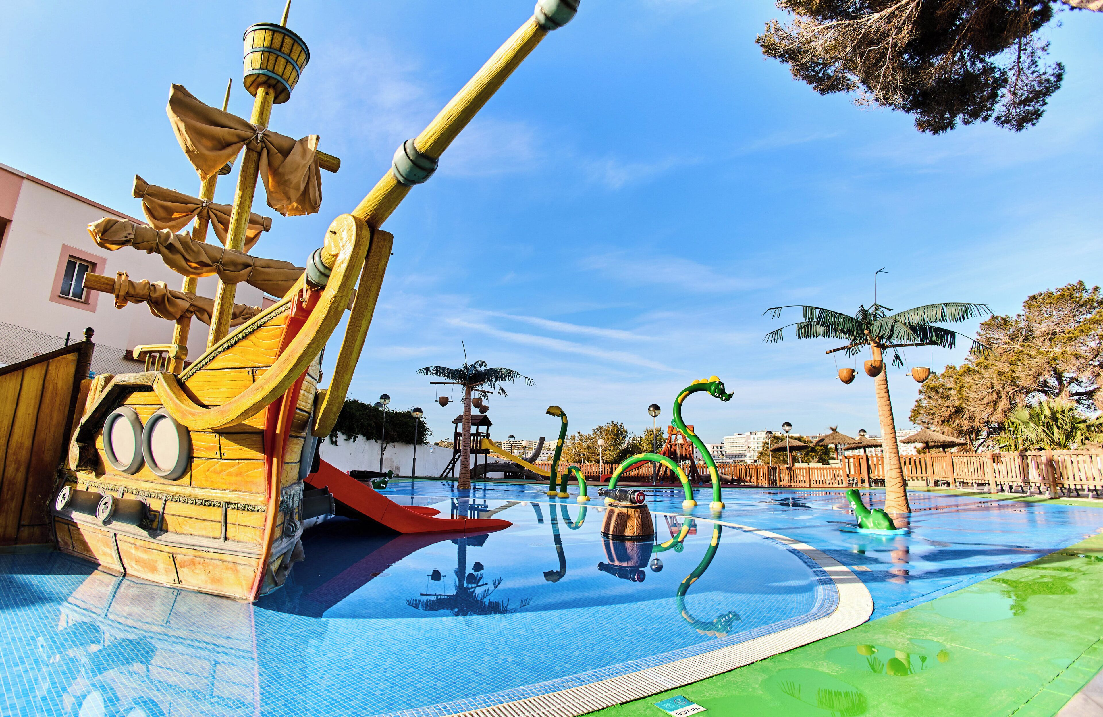 A water park with a pirate ship play structure, slides, and a pool.