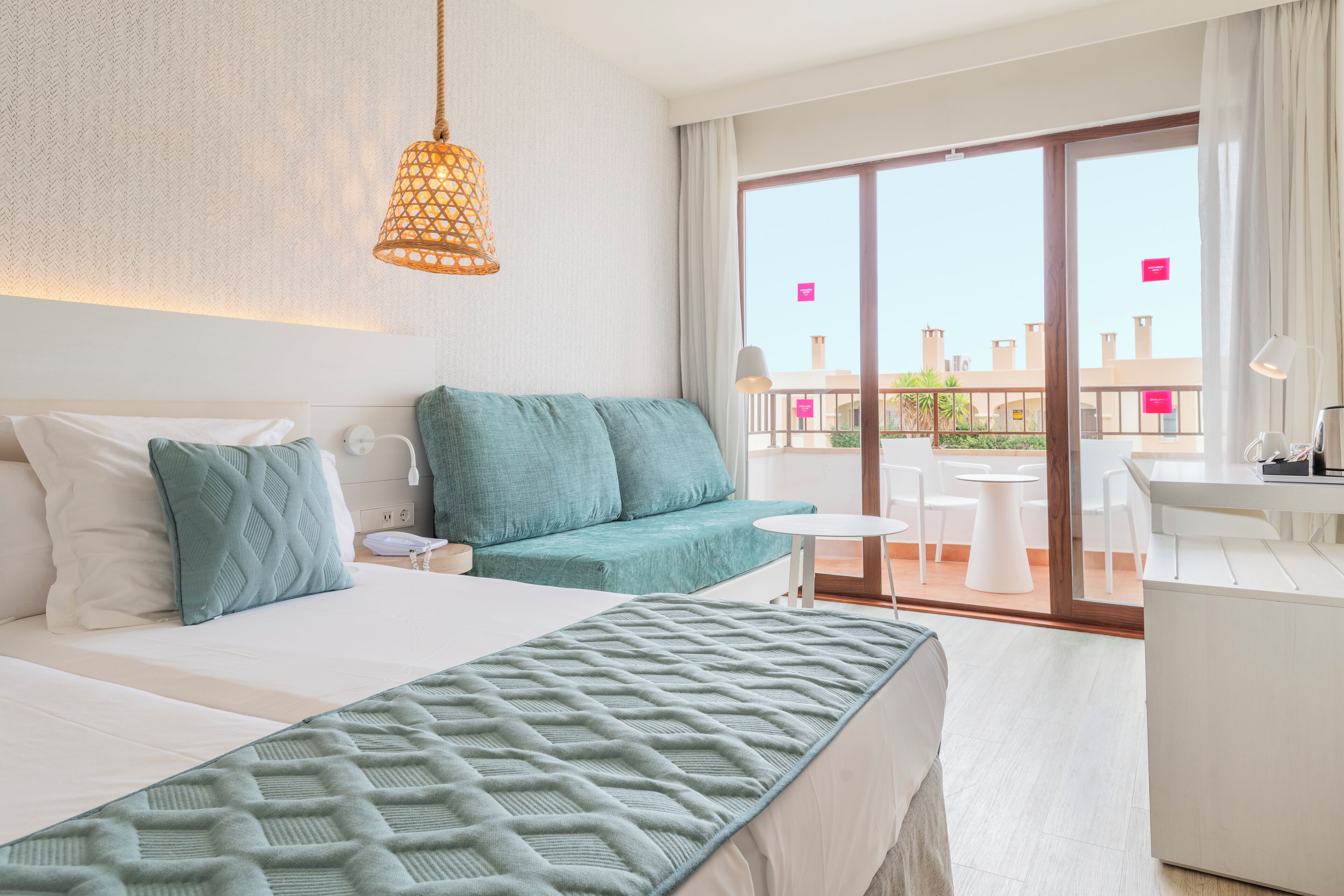 Habitación de hotel con cama, sofá, escritorio y balcón con vistas.