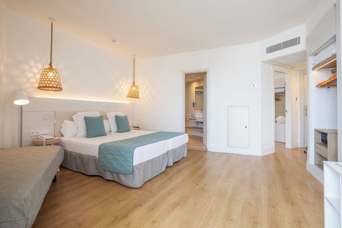 Een moderne slaapkamer met een groot bed, nachtkastjes en een inloopkast.