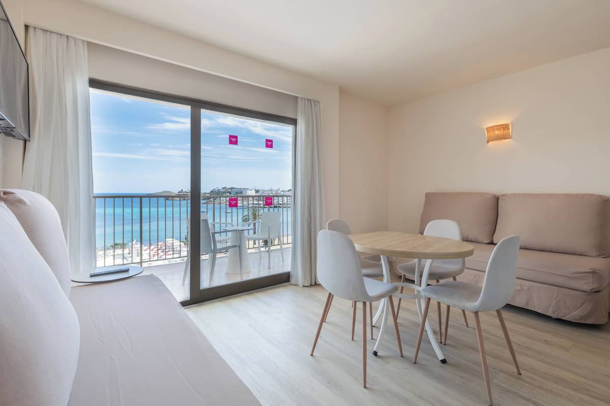 Een moderne hotelkamer met balkon, een zithoek en een bank.