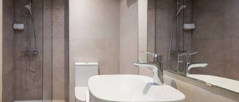 A modern bathroom with a freestanding bathtub, a toilet, and a shower area.