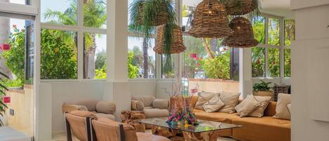 A spacious living room with a glass coffee table, leather sofas, and a large window with a view of greenery.