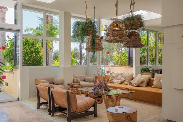 Ein großzügiges Wohnzimmer mit einem Glastisch, Ledersofas und einem großen Fenster mit Blick auf Grünflächen.