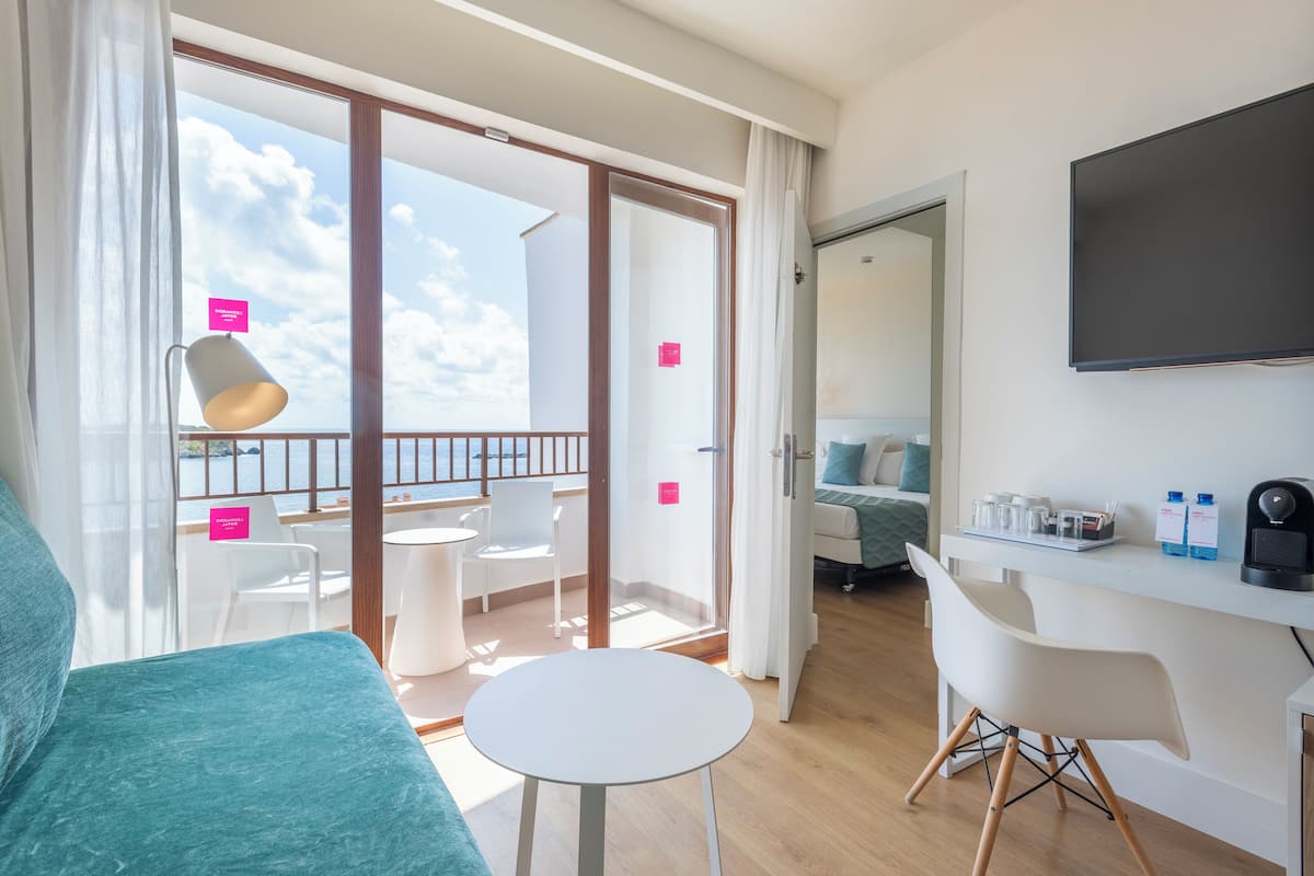 Een moderne hotelkamer met balkon, een bureau met flatscreen televisie en een gezellige zithoek.