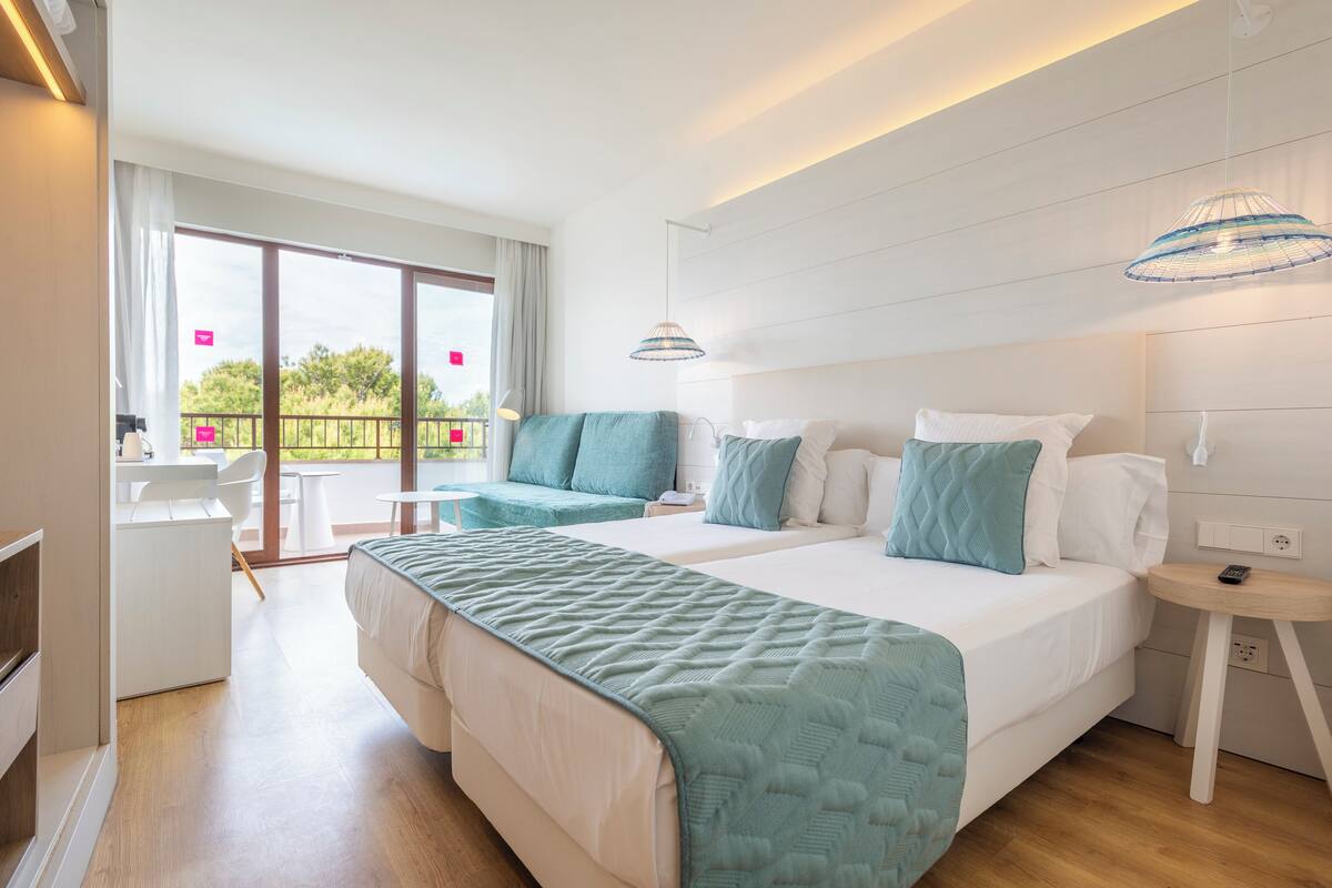 Een moderne hotelkamer met een groot bed, een bureau en een balkon met uitzicht.