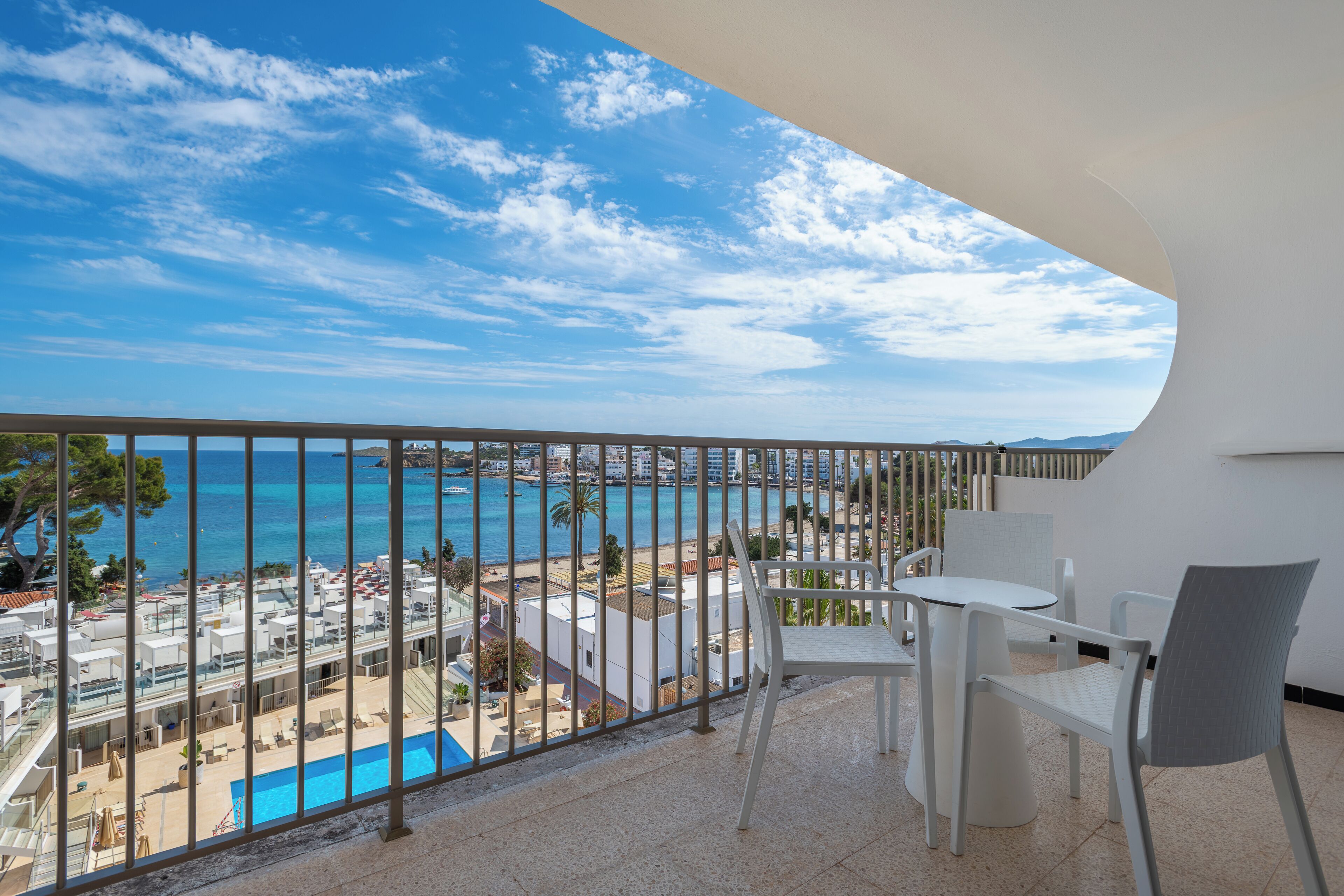 A balcony with a view of the sea and a pool area.
