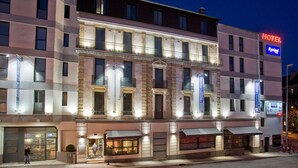 Un hotel con una fachada clásica, varios balcones y un llamativo letrero que dice 'HOTEL'.