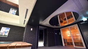 Un moderno vestíbulo de hotel con una recepción, una zona de piscina y una escalera que sube a un nivel superior.