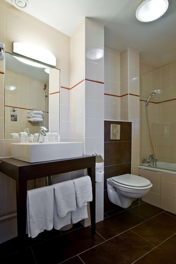 Un baño moderno con lavamanos, espejo, toallero, inodoro y ducha.