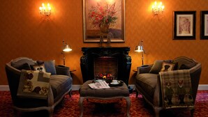 A cozy room with two armchairs, a fireplace, and a framed painting above it.