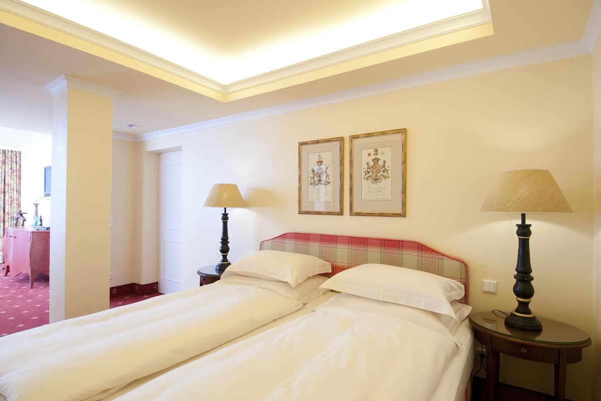 A hotel room with two beds, a red plaid headboard, two framed certificates on the wall, and two bedside lamps.