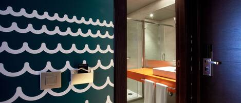 Un baño moderno con una pared con diseño de olas, un box de ducha de vidrio y una puerta de madera.
