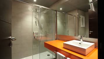 A modern bathroom with a glass-enclosed shower, a white sink, and an orange countertop.