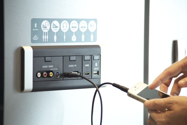Una estación de carga montada en la pared con varios puertos, incluyendo audio/video, HDMI y USB.