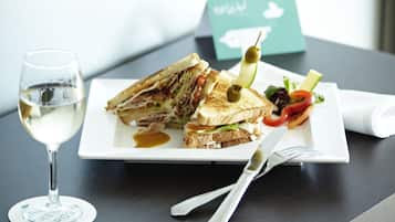 Un sandwich accompagné d’une salade et d’un verre de vin blanc, le tout servi sur une assiette.