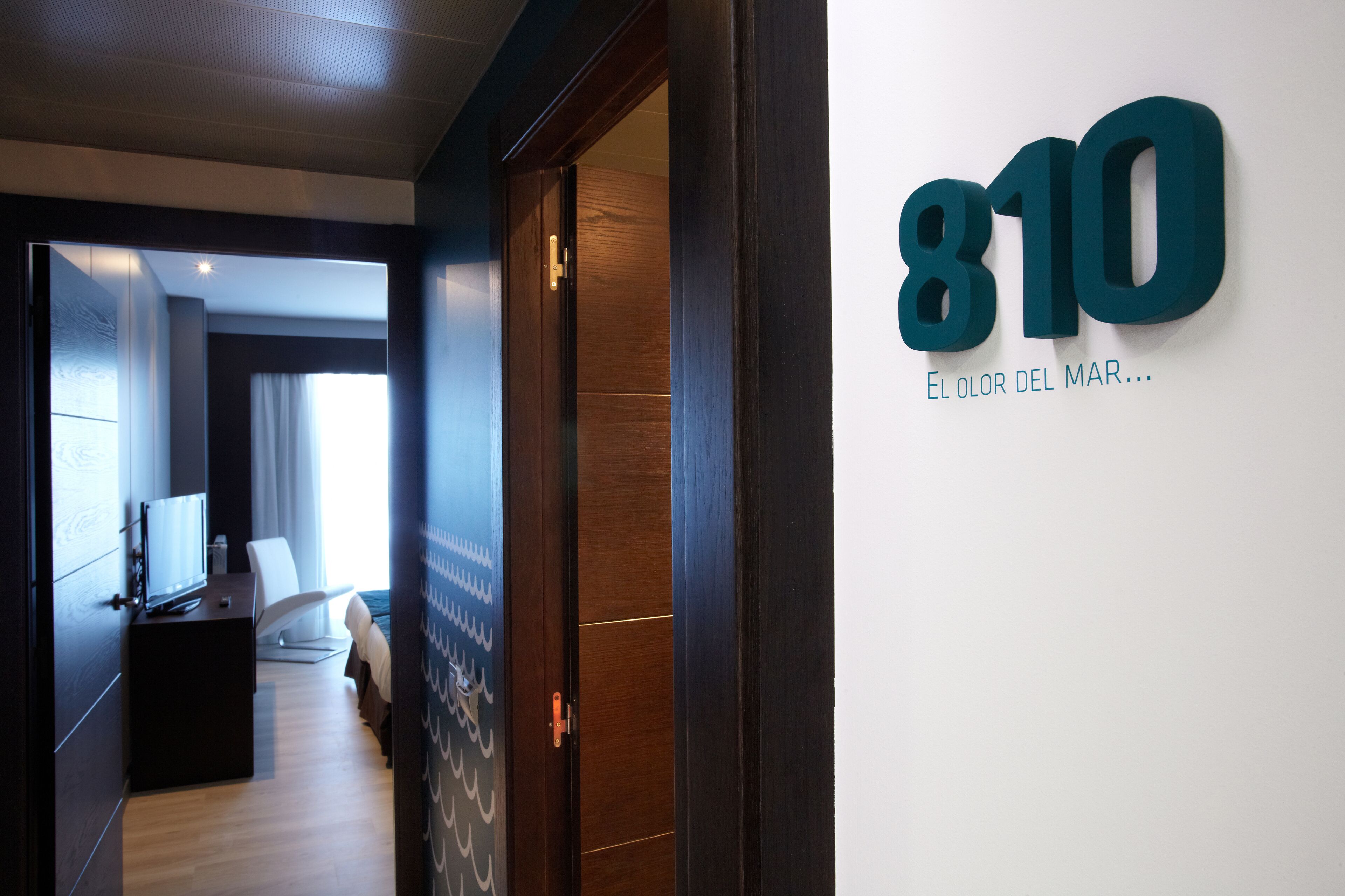 Ein Hotelzimmer mit Holztür, Fernseher, Bett und Fenster.