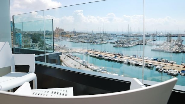 Habitación en un rascacielos con vistas panorámicas a un puerto deportivo lleno de barcos y yates.