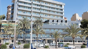 Un hotel de varios pisos con balcones, palmeras y cielo despejado.