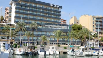 Un hotel con varios pisos, una marina con barcos y palmeras.