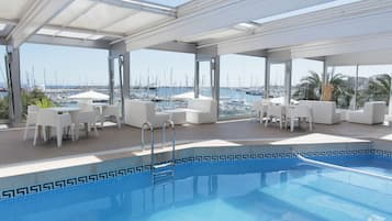 Relax by the pool with a view of the marina, surrounded by comfortable lounge chairs and shaded by a canopy.