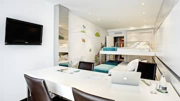Een moderne hotelkamer met een zithoek, een flatscreen televisie, een stapelbed en een kitchenette.