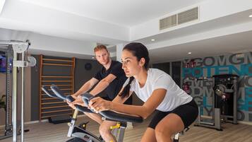 A gym with stationary bikes, a wall-mounted rack, and various exercise equipment.