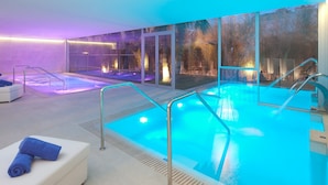 A modern indoor pool area with glass walls, a seating area with towels, and a spa-like ambiance. - Hotel JS Palma Stay - Adults Only (Palma de Mallorca)