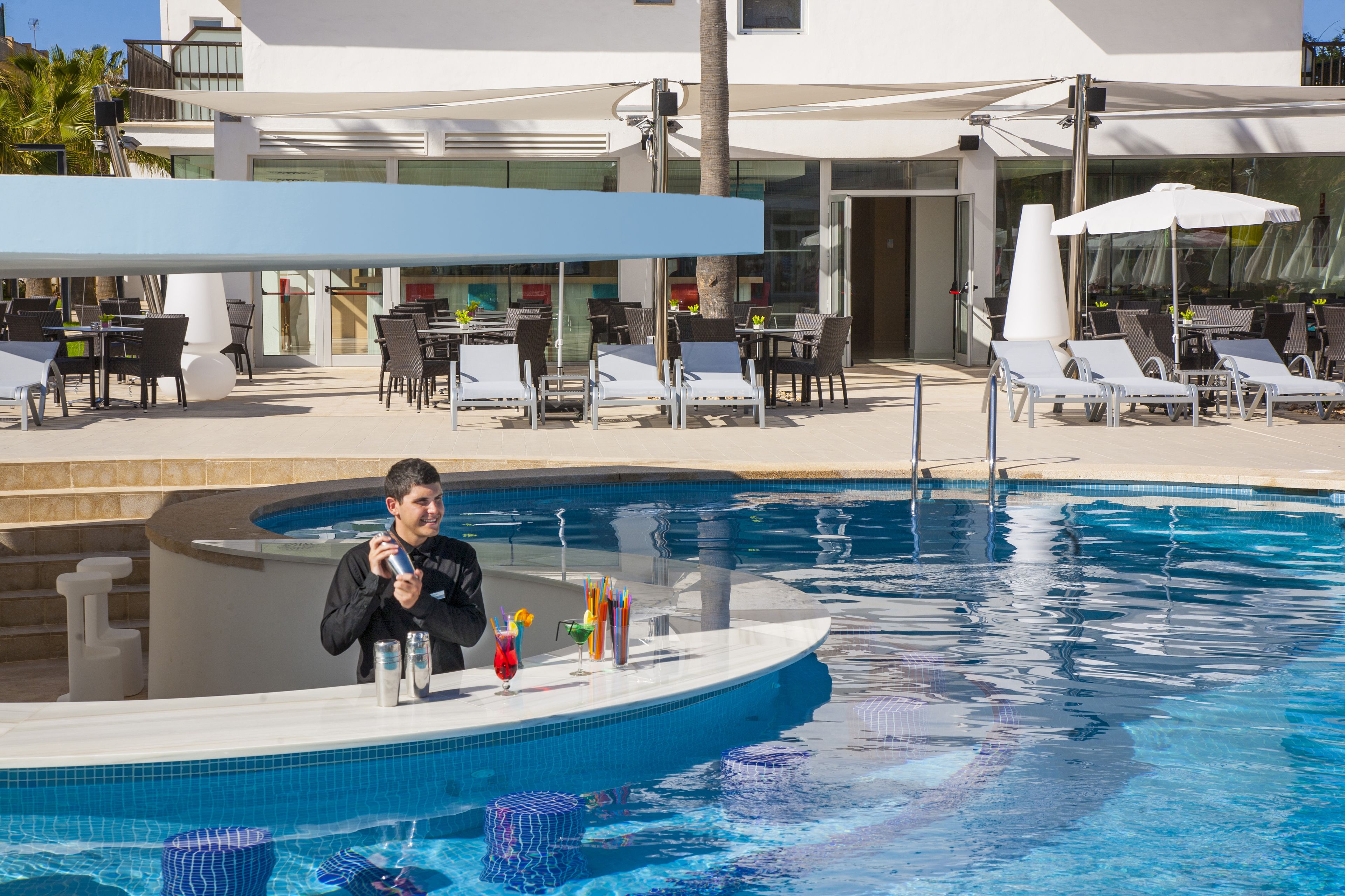 Un área junto a la piscina con sillones de descanso y un bar.