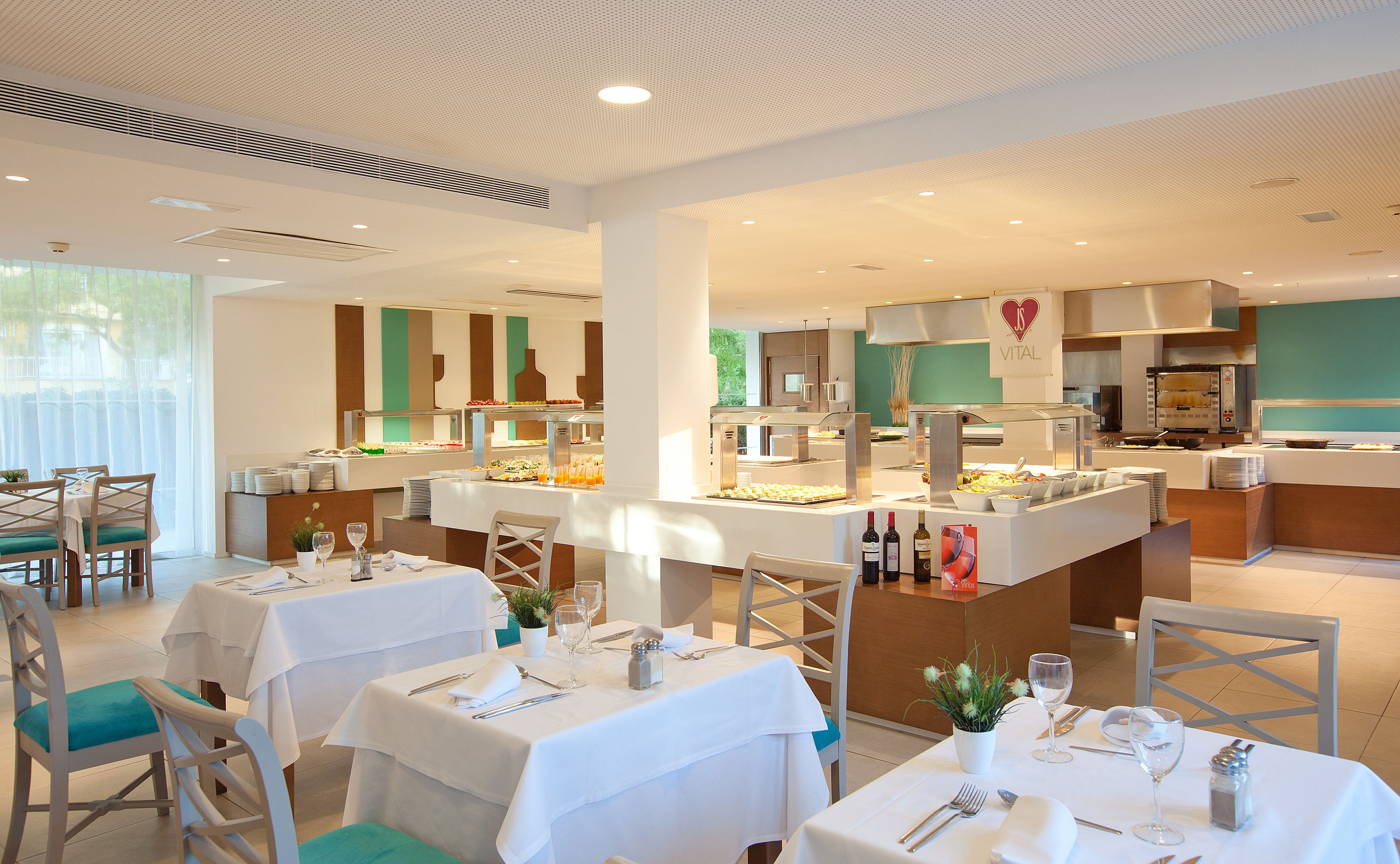 A restaurant with multiple dining tables, a buffet area, and a kitchen in the background.