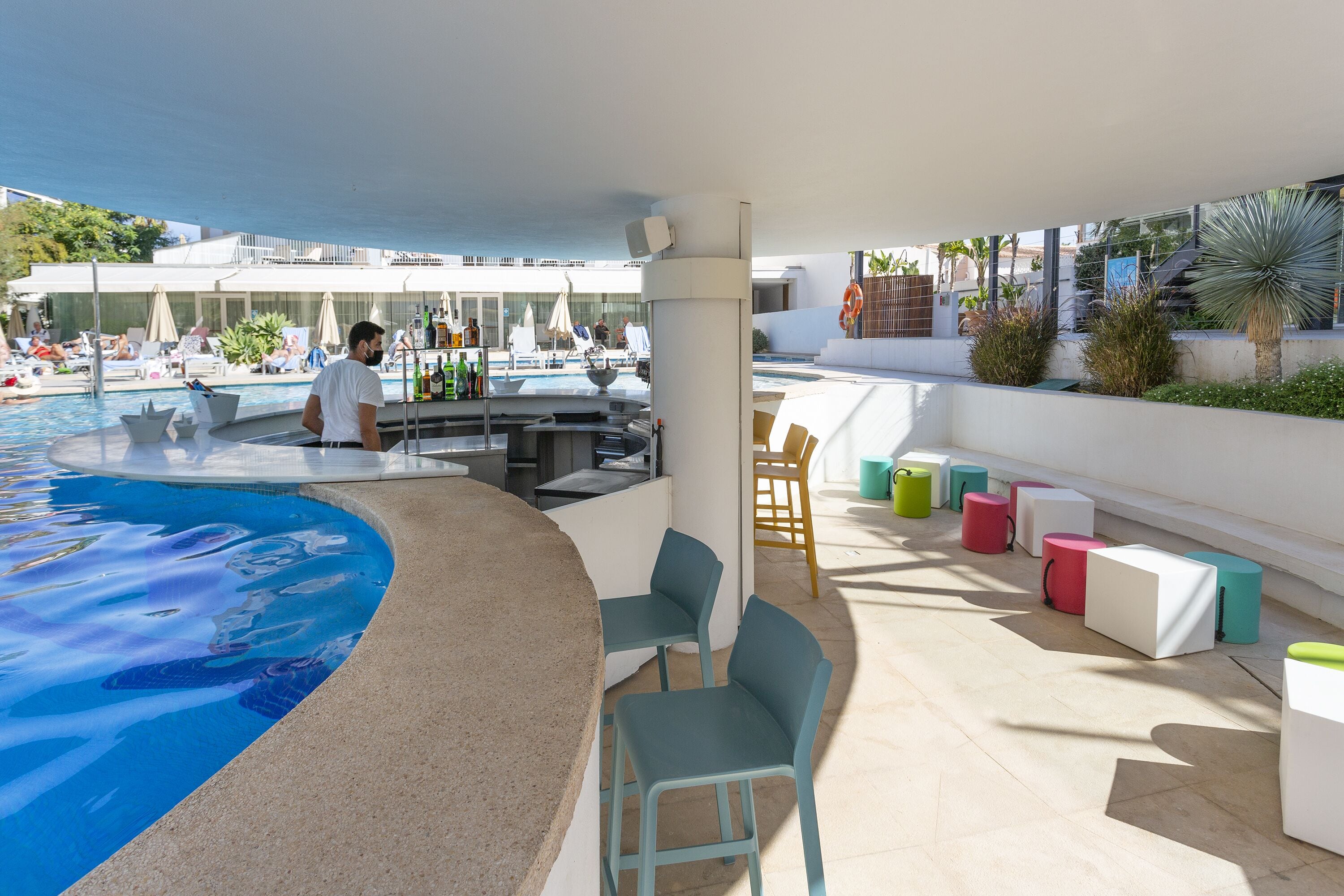 A poolside area with lounge chairs, a bar, and a pool with a unique design.