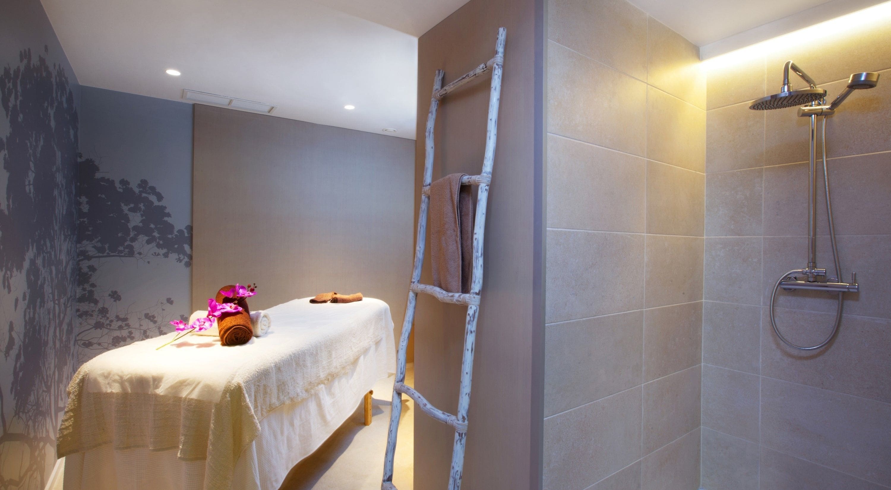 Un cuarto de spa con una camilla de masaje, toallas, una escalera y una ducha.