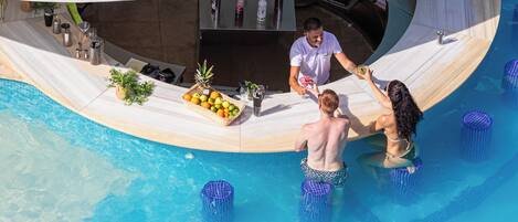 Un bar junto a la piscina con diseño circular, barra y zona de estar con planta y cesta de frutas.