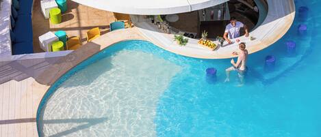 Un espace piscine au design incurvé, comprenant des zones aménagées pour s’asseoir et un bar.