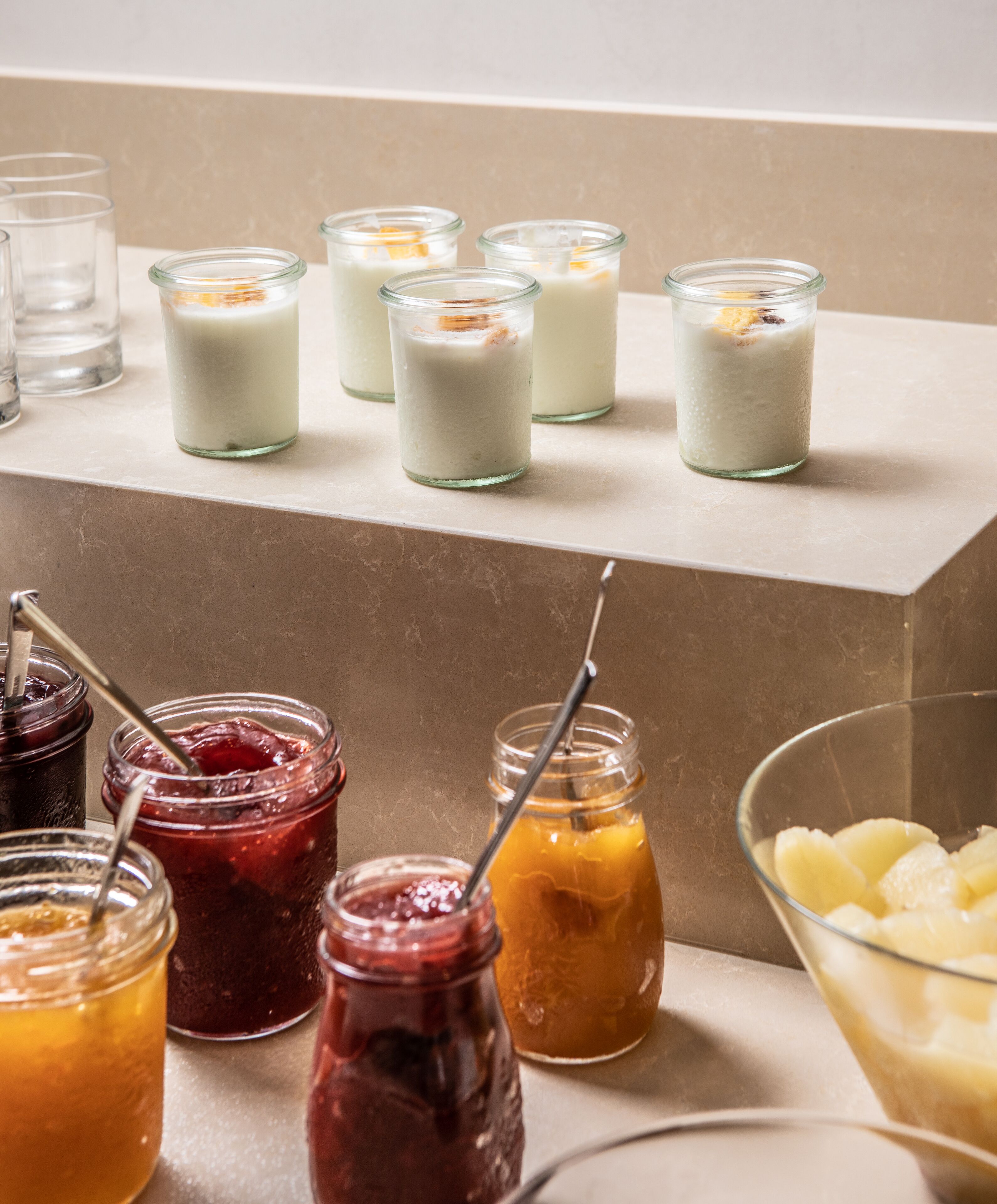 Una selezione di bevande tra cui frappè, succhi di frutta e marmellate, disposti su un bancone.