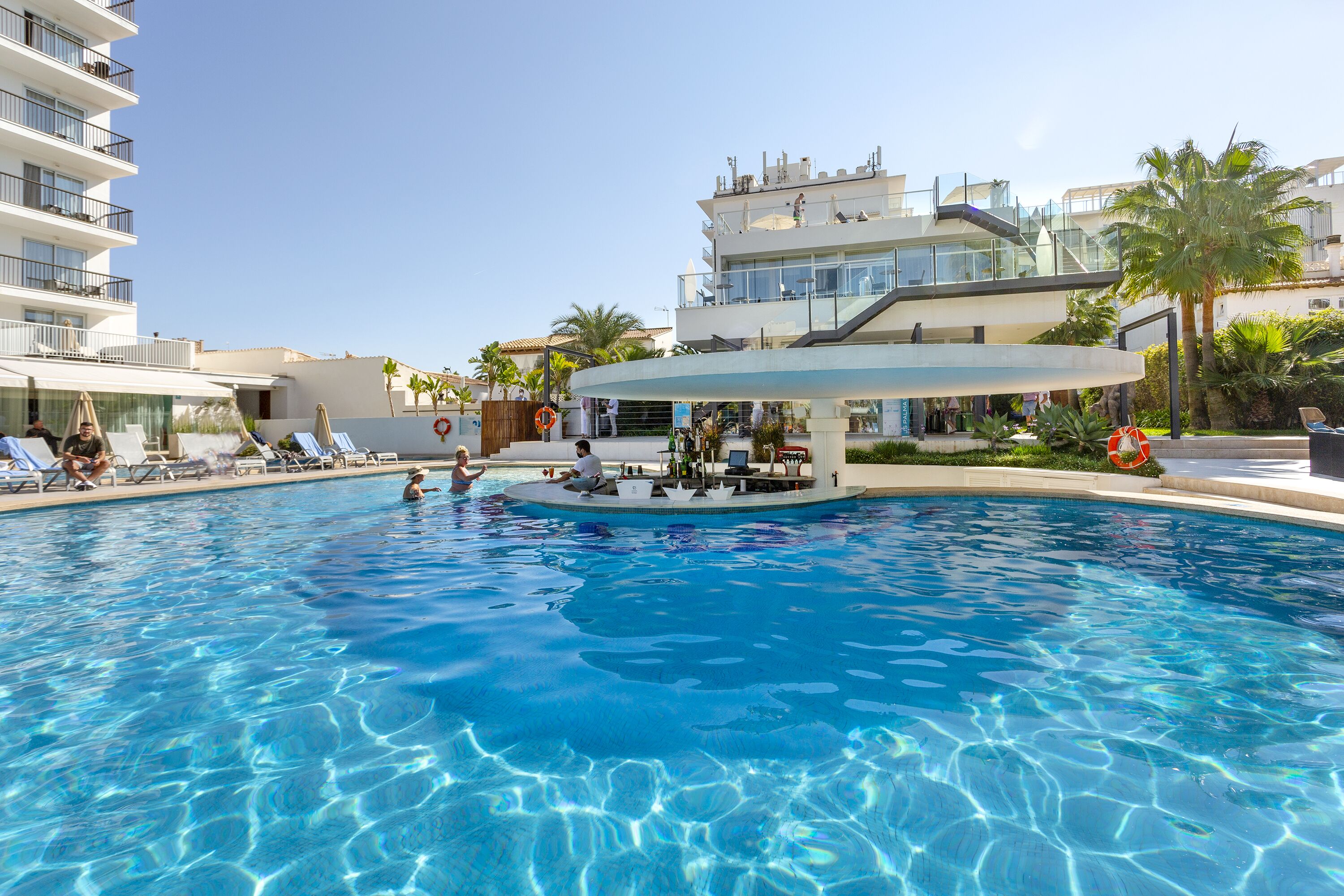 Una piscina con sillones de descanso y un área de bar.