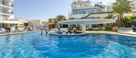 Una piscina con sillones de descanso y un área de bar.