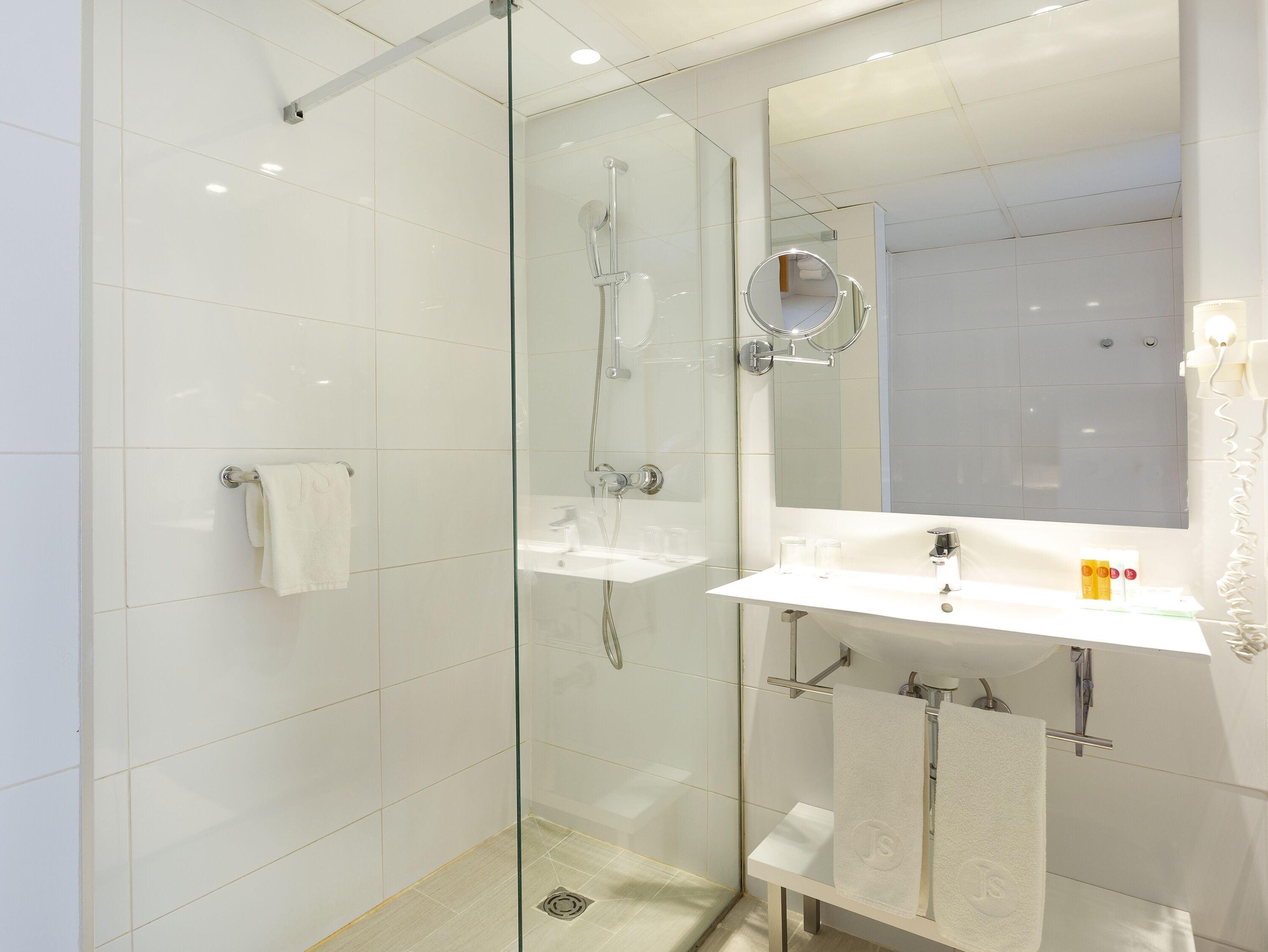 Une salle de bain moderne avec une douche à parois de verre, un lavabo blanc et un grand miroir.