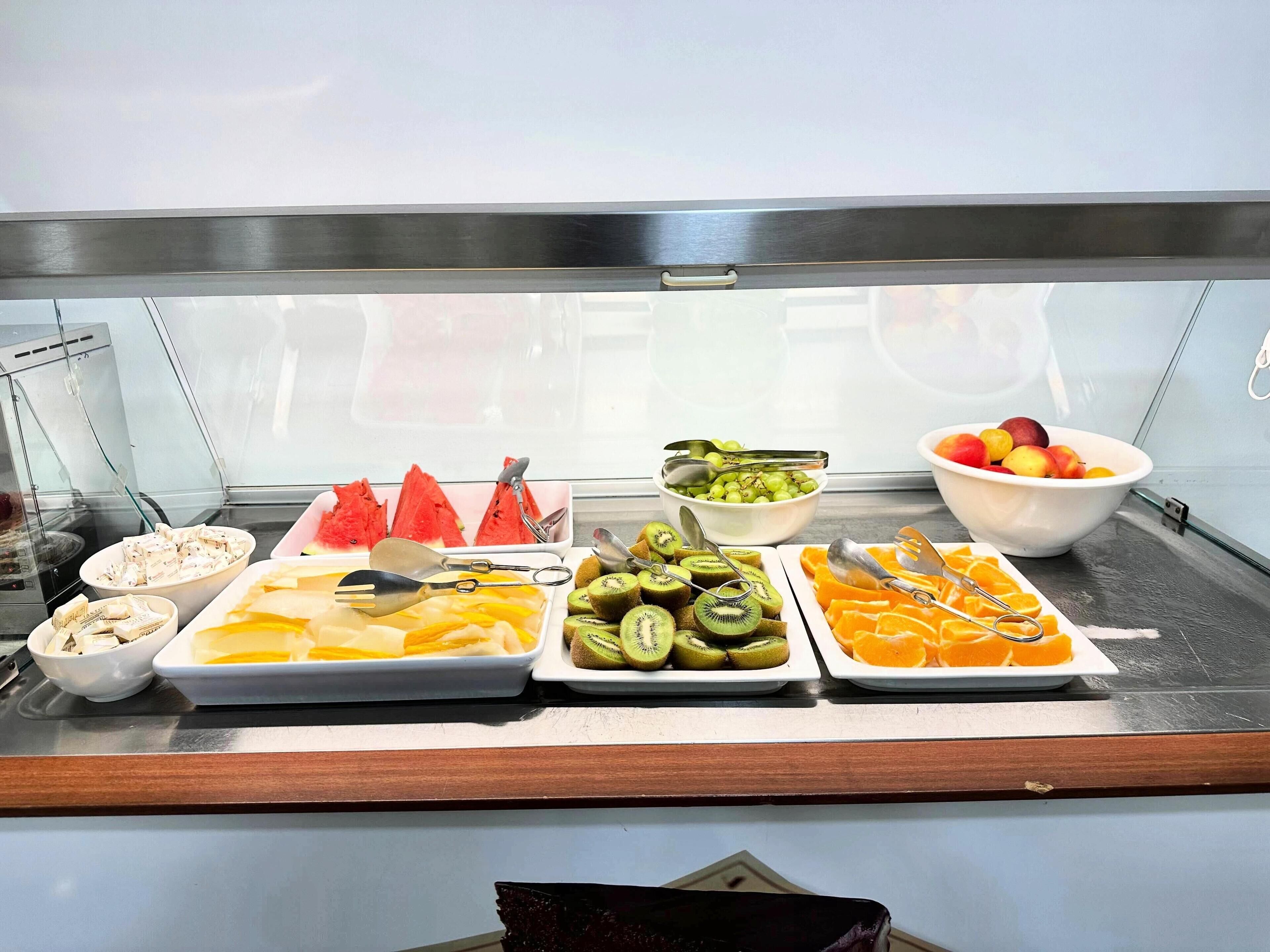 A buffet with various fruits and vegetables, including watermelon, kiwi, and oranges.