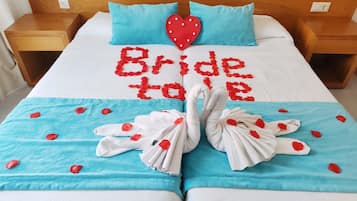 Una cama con una colcha azul, una decoración en forma de corazón rojo, y la frase 'Bride to be' escrita en rojo.