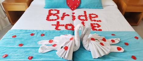Een bed met een blauwe spreideken, een rode decoratie in de vorm van een hart, en de tekst 'Bride to be' in rood.
